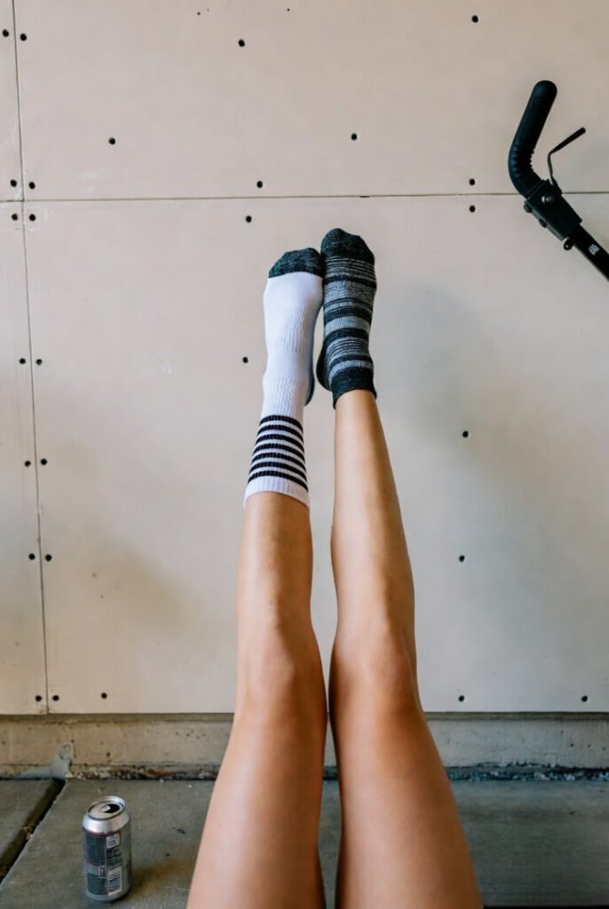 Legs up wall in messy garage, mismatched socks