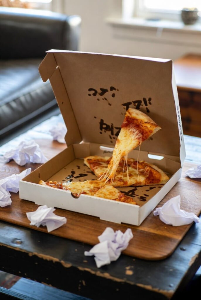 "Lazy weekend pizza aftermath, cheesy pull on coffee table"
